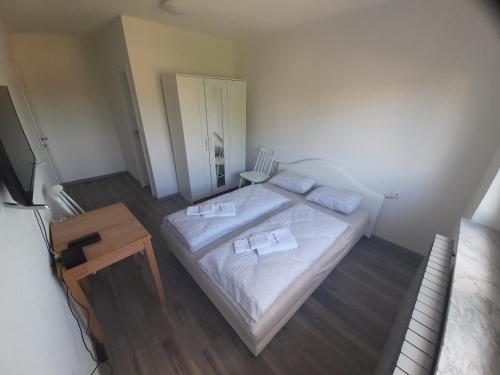 a small bedroom with a bed and a table at Apartmani Mamić in Tomislavgrad