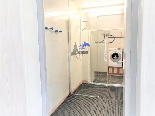 a bathroom with a shower and a washing machine at Charming traditional 2-Bed Cottage near Plemet in Plémet