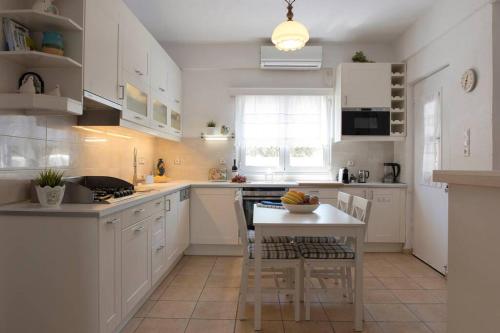 a kitchen with white cabinets and a table with chairs at Palmaya Villa, unique seafront experience in Vaia