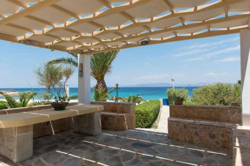 a patio with a bench and a view of the ocean at Palmaya Villa, unique seafront experience in Vaia
