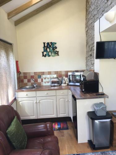 a kitchen with white cabinets and a couch in a room at Taliesin at The Poplars, Nr Saundersfoot in Pembrokeshire