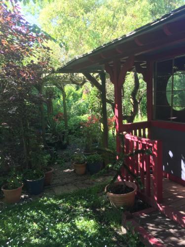 a garden with a red fence and potted plants at Taliesin at The Poplars, Nr Saundersfoot in Pembrokeshire