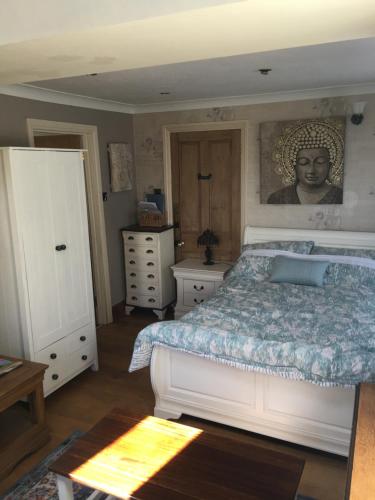 a bedroom with a bed and a painting on the wall at Taliesin at The Poplars, Nr Saundersfoot in Pembrokeshire
