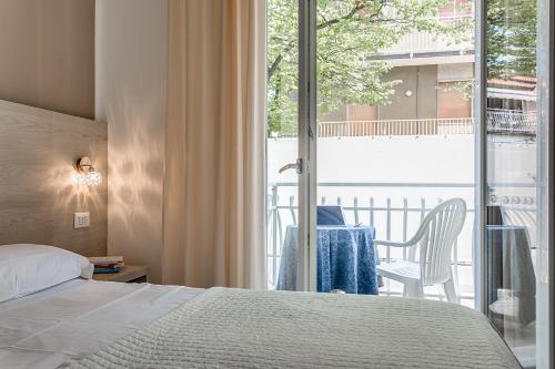 a bedroom with a bed and a balcony with a table at Anastasi Residence in Cervia