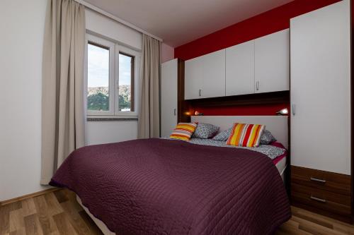 a bedroom with a purple bed and a window at Apartments Creska in Baška