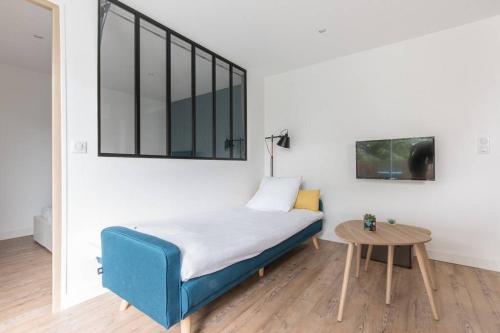 a bedroom with a blue bed and a table at Logement confort moderne au pied du Front de Mer in Saint-Nazaire
