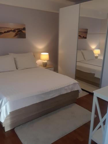 ein Schlafzimmer mit einem großen weißen Bett und einem Spiegel in der Unterkunft New Kosljun Apartment short walk to Beach in Košljun
