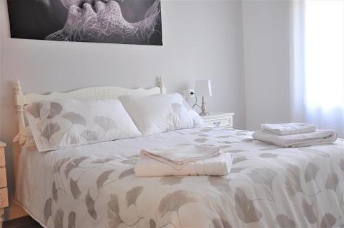 Una cama blanca con dos toallas encima. en SEVILLA I Y SEVILLA II, en La Guardia