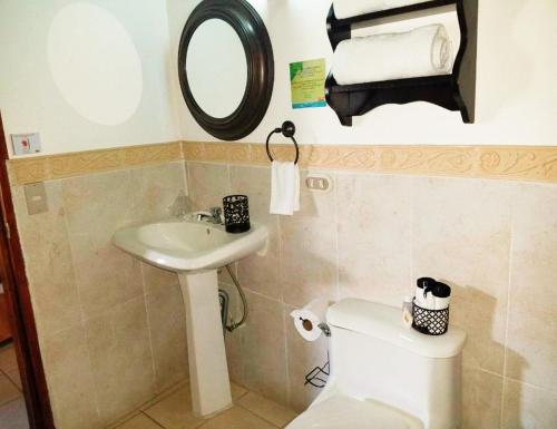a bathroom with a sink and a toilet and a mirror at Hostal Las Puertas in Santa Ana