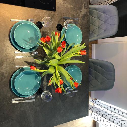 a table with green plates and red flowers on it at Apartament w Cieplicach Perfekt in Jelenia Góra