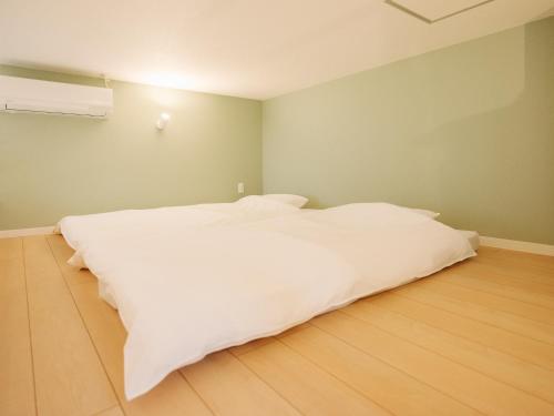 a white bed in a room with a wooden floor at REQRAS Sakuramachi - Vacation STAY 45081v in Kumamoto