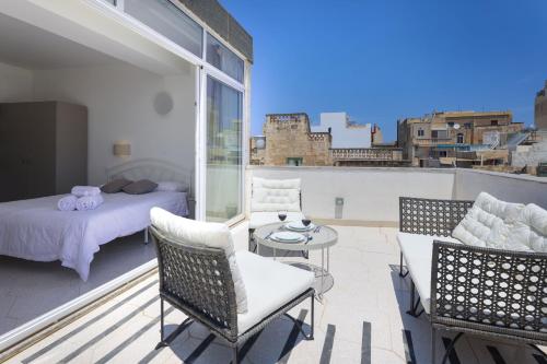 a balcony with a bedroom and a bed and a table at Ta Gianni Guest House in Sliema