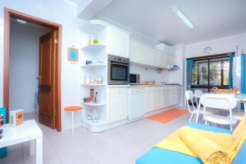 a kitchen with white cabinets and a table and chairs at Brasil Avenue by Rent4All in Figueira da Foz
