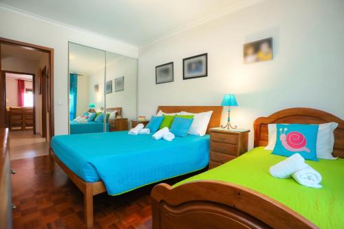 a bedroom with two beds with blue and green sheets at Brasil Avenue by Rent4All in Figueira da Foz