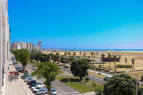 a city street with parked cars and the beach at Brasil Avenue by Rent4All in Figueira da Foz