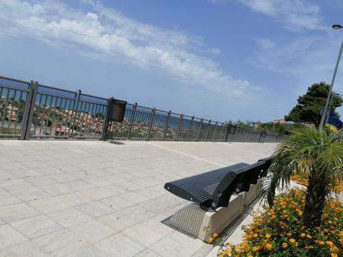 a park bench with a palm tree and a fence at Momaliar House in Campofelice di Roccella