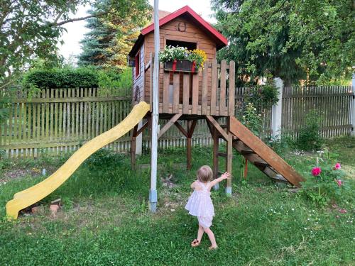 a little girl standing in front of a wooden playground at Ferienwohnung Prüfer in Greiz