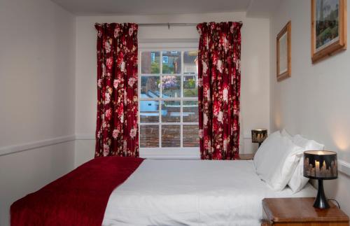 a bedroom with a bed with red curtains and a window at The Swan Hotel in Hythe