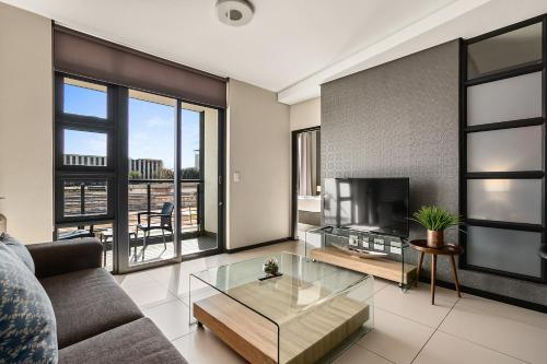 a living room with a couch and a television at Easy Stay - The Vantage Rosebank in Johannesburg