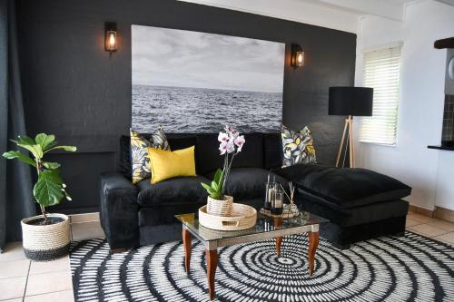 a living room with a black couch and a table at Palm Cove - 10 Thira, Santorini, best view over Thompsons Beach in Ballito