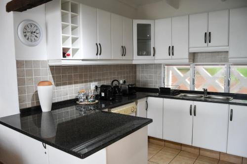 a kitchen with white cabinets and a black counter top at Palm Cove - 10 Thira, Santorini, best view over Thompsons Beach in Ballito