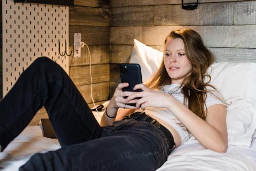 a woman sitting on a bed looking at her cell phone at Hostel Fish in Denver