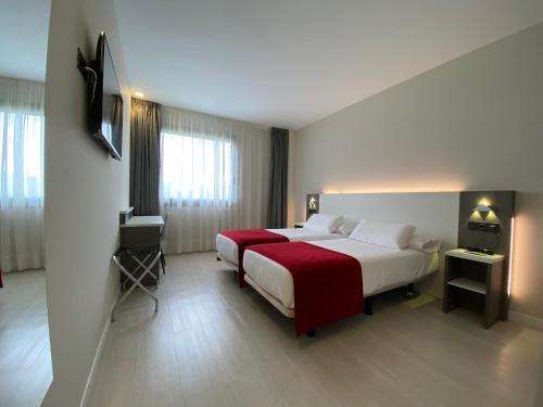 a hotel room with two beds and a television at Hotel New Bilbao Airport in Derio