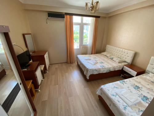 a small room with two beds and a television at Hotel Eurasia in Batumi