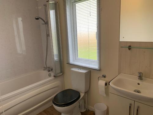 2 Bedroom Luxury Lodge, OG30, Shanklin, Isle of Wight في شانكلين: حمام ابيض مع مرحاض ومغسلة