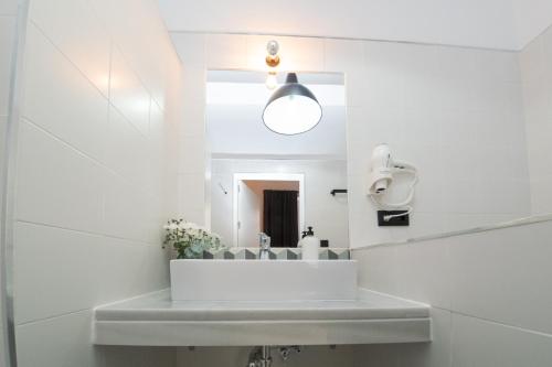 La salle de bains blanche est pourvue d'un lavabo et d'un miroir. dans l'établissement Casa Miguel - Apartamento 3, à Sanlúcar de Barrameda