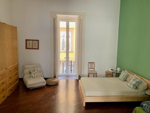 a bedroom with a bed and a chair and a window at Casa del Plebiscito in Naples