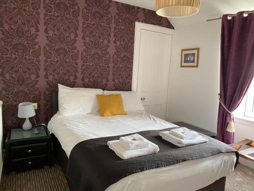 a bedroom with a bed with two towels on it at Richmond House Hotel in Fort Augustus