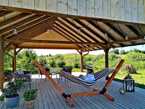 a woman sitting in a hammock on a patio at Domki Mazurska Dolina in Mikołajki