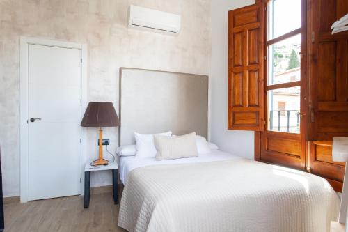 a bedroom with a bed and a lamp and a window at Sueño de Elvira in Granada