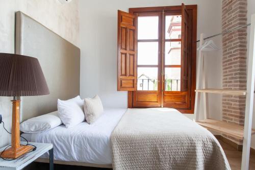 a bedroom with a bed with a lamp and a window at Sueño de Elvira in Granada