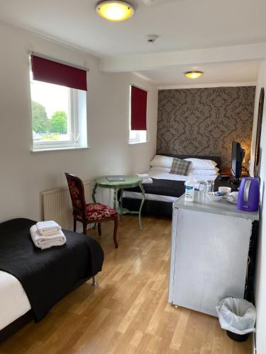 a room with two beds and a desk and a table at Richmond House Hotel in Fort Augustus