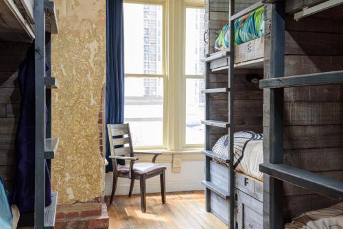 a bedroom with bunk beds and a chair and a window at Hostel Fish in Denver
