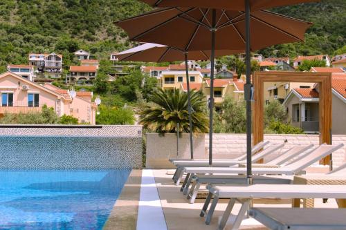 a group of chairs with umbrellas next to a swimming pool at Sun Village Aparthotel in Herceg-Novi