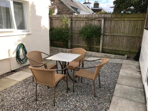 un patio avec une table et des chaises et une clôture dans l'établissement No 10 The Cottage, à Inverness
