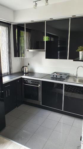 una cocina con armarios negros y fregadero en Apartament New Jork, en Olsztyn