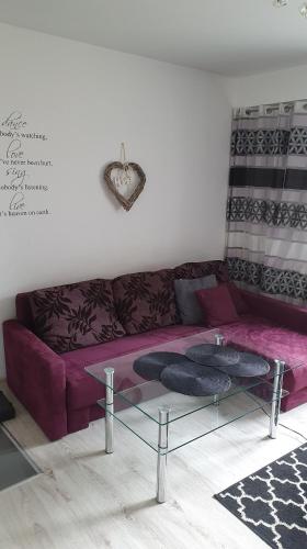 a living room with a purple couch and a glass table at Apartament New Jork in Olsztyn