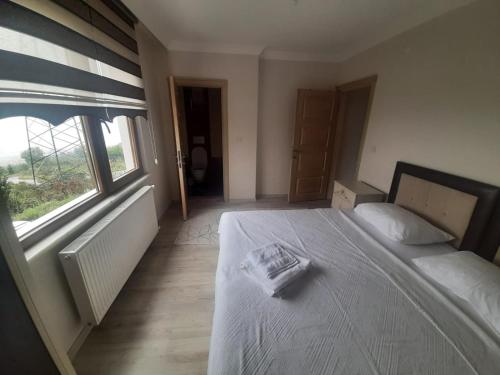 a bedroom with a bed with a white blanket and a window at Menekşe Apart 2 in Trabzon