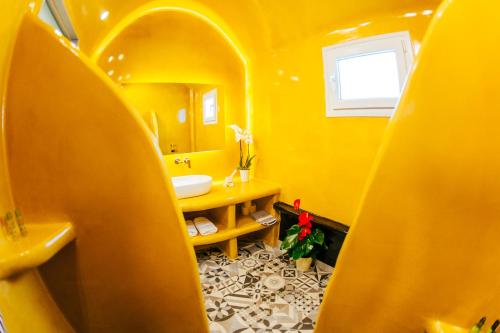 Baño amarillo con lavabo y espejo en Floresita apartment, en Fira