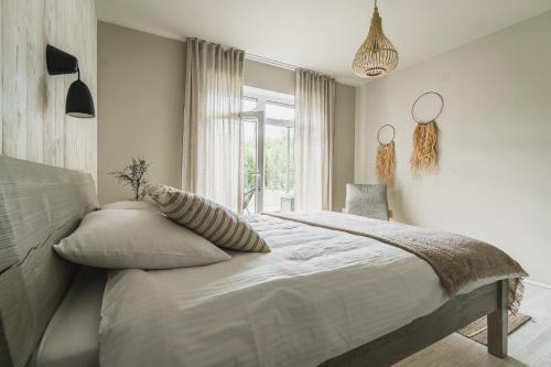 a bedroom with a large white bed with pillows and a window at Guest House Garoza with Self Check-in in Tūja