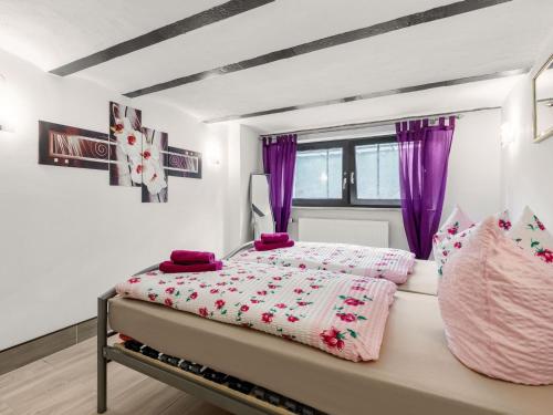 a bedroom with a bed with pink sheets and purple curtains at Cosy apartment in Grevesmühlen with parking in Grevesmühlen