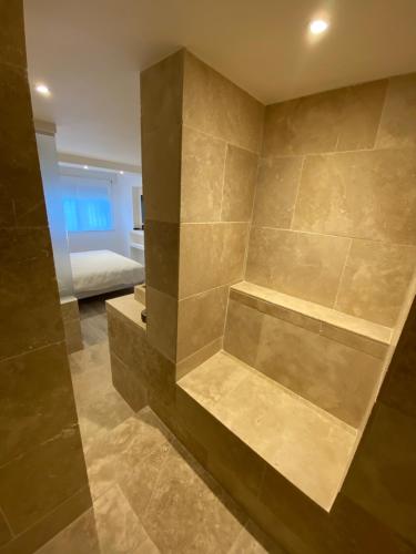 un bagno con parete in pietra e un letto in una camera di Feel@Home Nemausus « Le 21 » a Nîmes