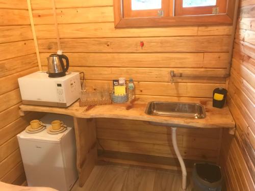 a small kitchen with a sink and a microwave at Cabana da Colina in Bom Jardim da Serra