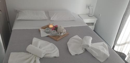 um quarto com uma cama com toalhas brancas e uma bandeja com uma vela em Hotel Anezina em Drios