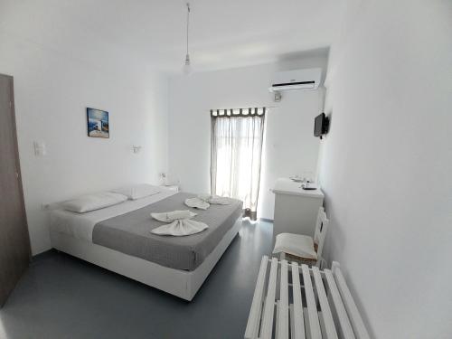 a white bedroom with a bed and a window at Hotel Anezina in Drios