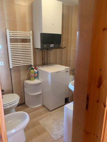 a bathroom with a toilet and a tv on the wall at La Majonetta in Champoluc